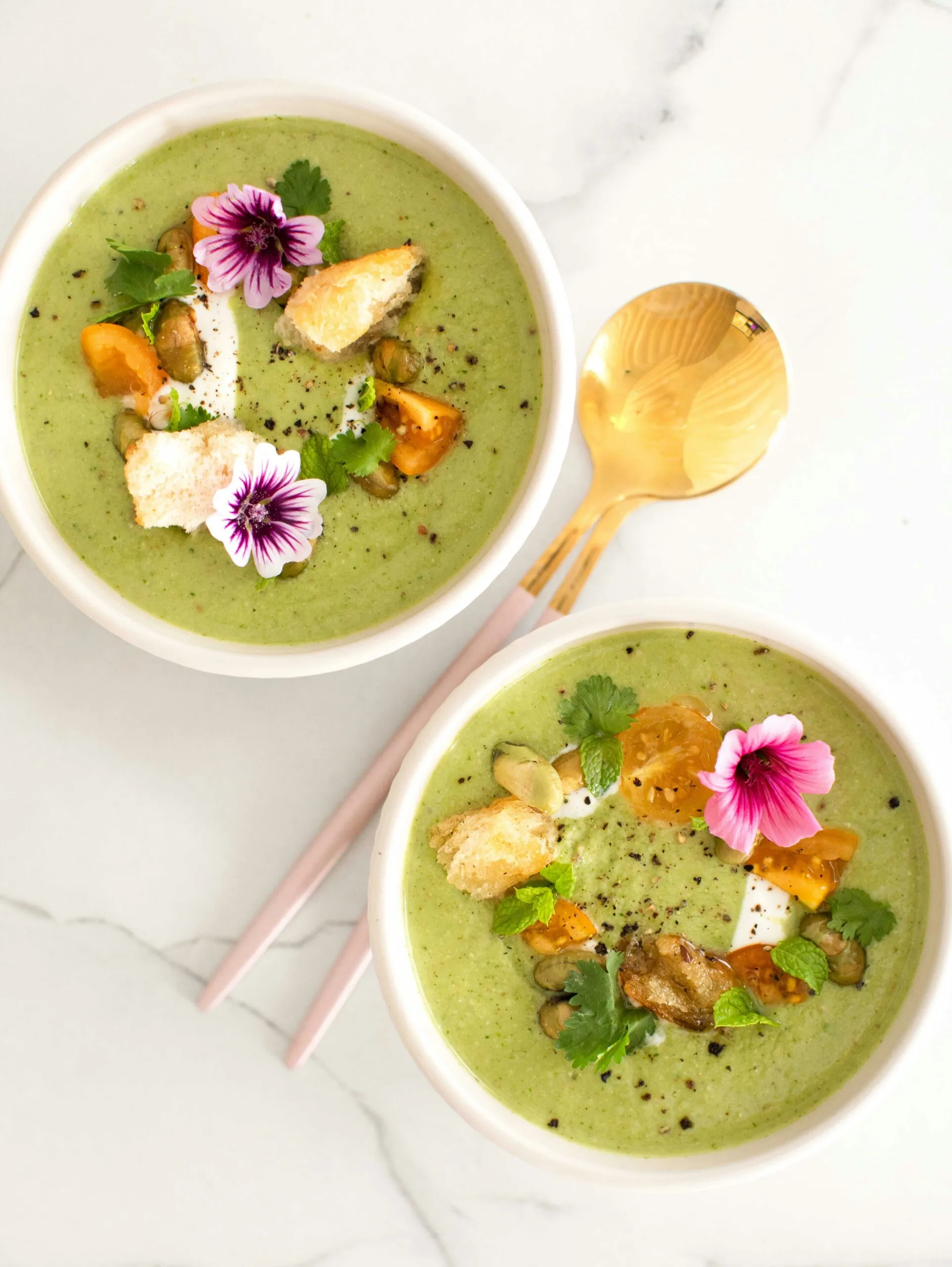 Deux bols de gaspacho aux fèves et à la menthe, garnis de feuilles de menthe fraîche